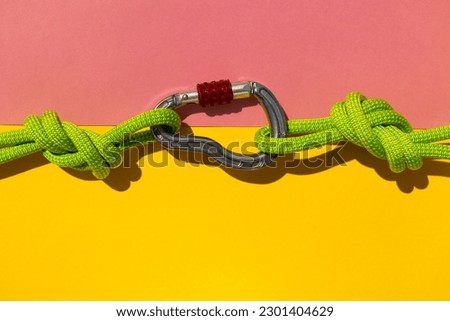 carabiner with a rope lies on a colored background. Equipment for climbing and mountaineering. reliable connection. Safety rope. Node eight. the concept of reliability and strength. copy space.