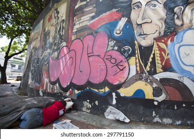 CARACAS, VENEZUELA, APRIL 20: Unrecognizable Poor Man Sleeping On The Street Of Downtown Caracas With A Graffiti Of Simon Bolivar. The Poverty In Venezuela In Very High Due To The Inflation In 2015.