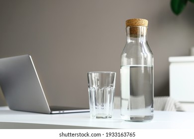 A carafe of clean water and a glass on the desktop, sunlight and a healthy lifestyle concept