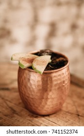 Caramel Apple Moscow Mule Cocktail Garnished With Apples And Cinnamon On Rustic Background