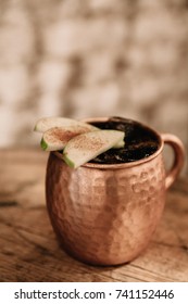 Caramel Apple Moscow Mule Cocktail Garnished With Apples And Cinnamon On Rustic Background