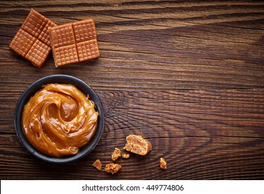 Caramel Candies And Sweet Sauce On Wooden Table, Top View