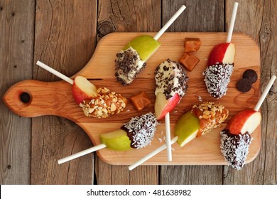 Caramel And Chocolate Dipped Apple Slices On A Paddle Board With Rustic Wooden Background