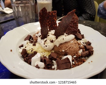 Caramel Chunks Sunken In A Vanilla-chocolate Ice Cream With Broken Brownies On A White Ceramic Plate