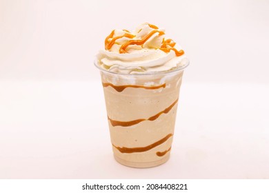 Caramel flavoured frappe served in a plastic cup with whipped cream and dressing.  