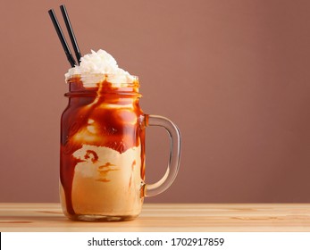 caramel milkshake with coffee on wooden table. Salted caramel ice cream sundae. Cold coffee drink frappe frappuccino , with whipped cream
