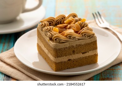 A Caramel Mocha Mini Cake Topped With Almonds Served On A White Plate Together With A Cup Of Coffee As Background For A Coffee Break Time. 