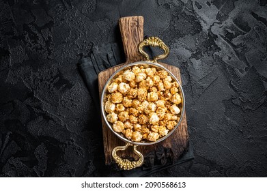 Caramel Popcorn in rustic bowl. Black background. Top view