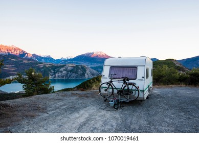 Caravan With A Bike Parked On A Mountaintop With A View On The French Alps Near Lake Lac De Serre-Poncon