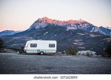 Caravan With A Bike Parked On A Mountaintop With A View On The French Alps Near Lake Lac De Serre-Poncon