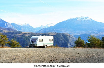 Caravan With A Bike Parked On A Mountaintop With A View On The French Alps Near Lake Lac De Serre-Poncon On A Bright Sunny Day