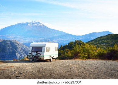 Caravan With A Bike Parked On A Mountaintop With A View On The French Alps Near Lake Lac De Serre-Poncon On A Bright Sunny Day