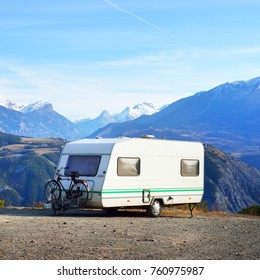 Caravan With A Bike Parked On A Mountaintop With A View On The French Alps Near Lake Lac De Serre-Poncon On A Bright Sunny Day