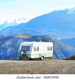 Caravan With A Bike Parked On A Mountaintop With A View On The French Alps Near Lake Lac De Serre-Poncon On A Bright Sunny Day