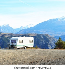 Caravan With A Bike Parked On A Mountaintop With A View On The French Alps Near Lake Lac De Serre-Poncon On A Bright Sunny Day