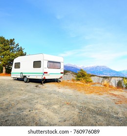 Caravan With A Bike Parked On A Mountaintop With A View On The French Alps Near Lake Lac De Serre-Poncon On A Bright Sunny Day