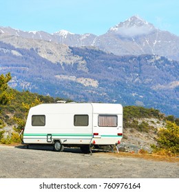 Caravan With A Bike Parked On A Mountaintop With A View On The French Alps Near Lake Lac De Serre-Poncon On A Bright Sunny Day