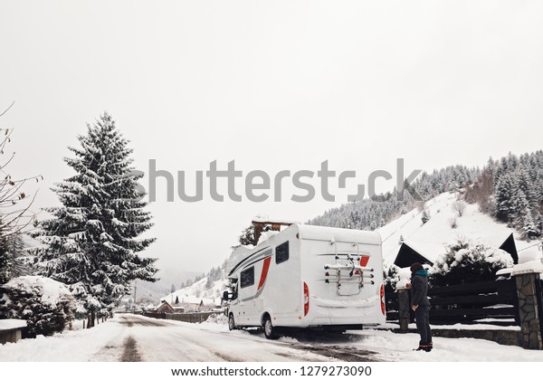 caravan camper\
van vehicle for van life  winter holidays on camper van journey\
camping in mountains near the forest in the winter adventure\
season, snowing on the\
campervan
