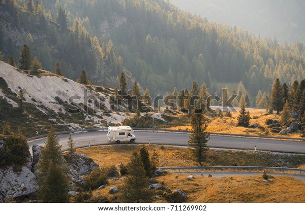 Caravan car\
travels on a mountain road at\
sunset