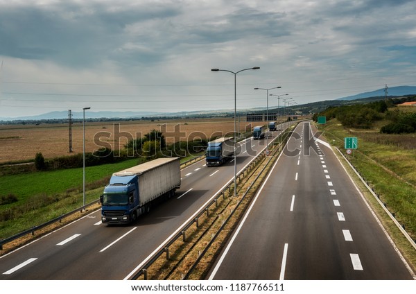 Caravan or convoy of lorry trucks in line on a\
country highway