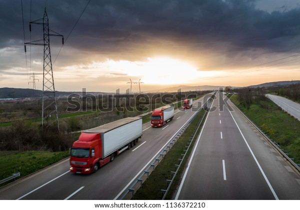 Caravan or convoy of red trucks in line on a\
country highway