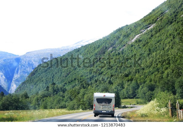 Caravan or recreational vehicle motor home\
trailer on a mountain road in Norway. RV, pandemic-related travel\
restrictions concept.