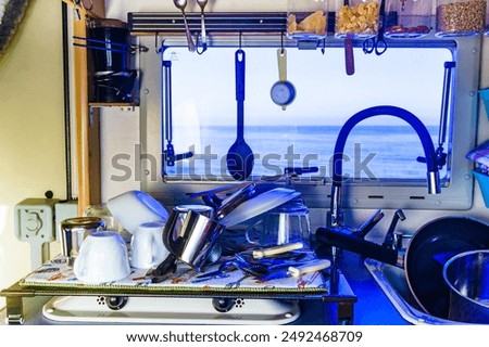 Caravan rv inside, dishwashing in kitchen. Many clean dishes on dish drying mat after washing up. Longing for an rv dishwasher. Holidays, travel and camping. Van life lifestyle.