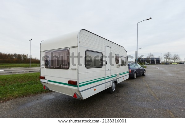 Caravan\
trailer and a car parked near the empty highway through green\
fields. Transportation, RV, motorhome, camping, eco tourism,\
recreation, alternative lifestyle,\
wanderlust