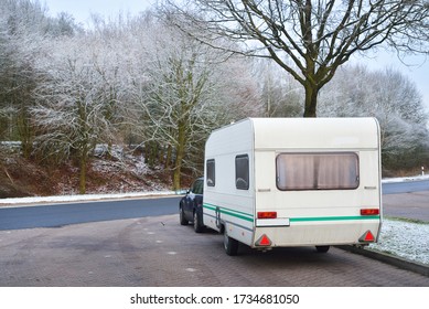 Caravan Trailer And A Car Parked Under The Frosty Tree. Bicycle Road And City Park In The Background. Germany. Christmas Vacations, Recreation Theme