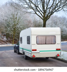 Caravan Trailer And A Car Parked Under The Frosty Tree. Bicycle Road And City Park In The Background. Germany. Christmas Vacations, Recreation Theme