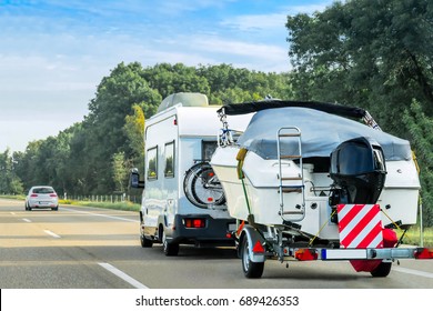 Caravan and trailer for motor boats on the road in Switzerland.