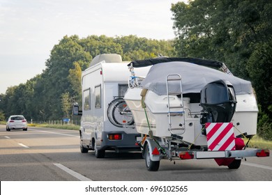 Caravan with trailer for motor boats on road in Switzerland.