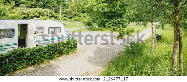 Caravan trailer parked\
in a green park on a clear sunny day. Camping site. Road trip,\
vacations, eco tourism