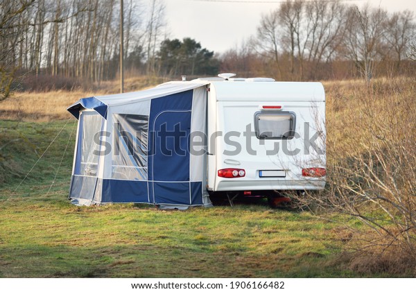 Caravan trailer parked on a green lawn in a\
small village on a clear spring day. Normandy, France.\
Transportation, RV, motorhome, road trip, local travel, ecotourism,\
recreation, leisure\
activity
