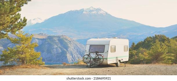 Caravan trailer parked on a mountaintop with a view on French Alps near lake Lac de Serre-Poncon. Transportation, RV, motorhome, road trip, camping, tourism, recreation, lifestyle - Shutterstock ID 2184695921