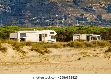 Vehículos de caravana acampando en la costa del mar. Dunas de playa de arena y montañas. Región mediterránea de la Costa del Sol, España.