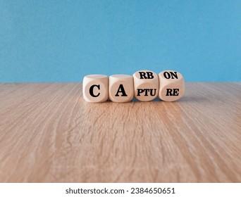 Carbon capture symbol. Turned wooden cubes and changed the concept word Carbon to Capture. Beautiful wooden table blue background. Business ecological carbon capture concept. Copy space.