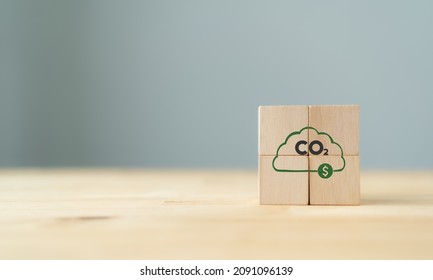 Carbon credit concept. Tradable certificate to drive industrial and commercial processes in the direction of low emissions or less carbon in efficiency cost.  The wooden cubes with CO2 and US dollars. - Shutterstock ID 2091096139