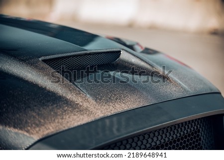 Carbon fiber car hood with a hood scoop viewed from the front at an angle