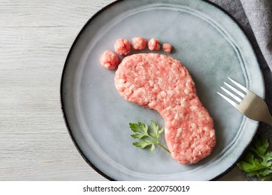 Carbon footprint concept, meat consumption and CO2 emissions, meat on foot-shaped plate, abstraction  - Shutterstock ID 2200750019