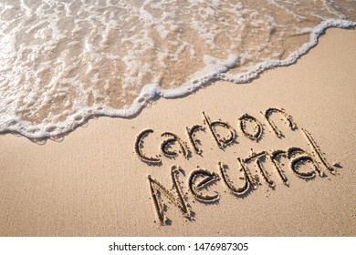 Carbon Neutral Message Handwritten On Smooth Sand Beach With Incoming Wave