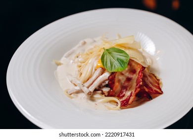 Carbonara Pasta With Bacon And Cream Sauce. Decorated With Egg Yolk And Basil.