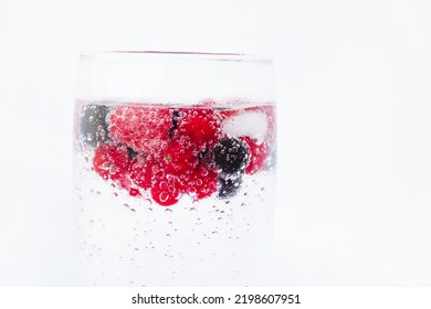 Carbonated drinks with fresh berries and ice. Fresh cold sparkling bubble water with raspberry, black and red currant berries in transparent glass with ice, angle view macro. Food and drink concept - Powered by Shutterstock