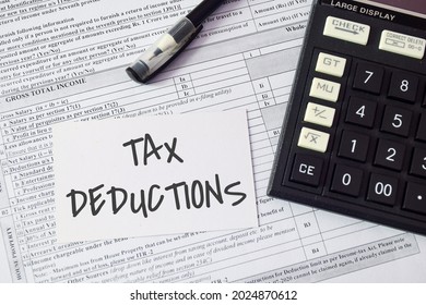 A card with the note TAX DEDUCTIONS placed on income tax return form with calculator. TDS payment concept.  - Shutterstock ID 2024870612