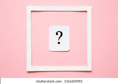 
Card of question mark in white frame on pastel pink background. Soft light color. Women issues. Problem and solution concept.