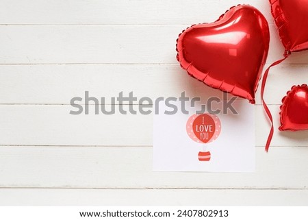 Card with text I LOVE YOU and heart shaped balloons on white wooden background. Valentines Day celebration