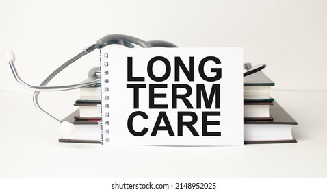 Card With Word Long Term Care, Stethoscope, Face Masks And Flower On Table