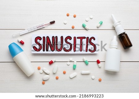 Card with word SINUSITIS, thermometer and different drugs on white wooden background, flat lay