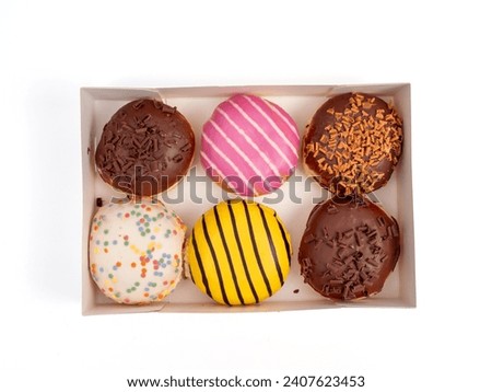 Cardboard box with donuts of different flavors isolated on a white background. Sweet buns on a white background.
