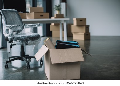 cardboard box with folders and office supplies in floor during relocation - Shutterstock ID 1066293863
